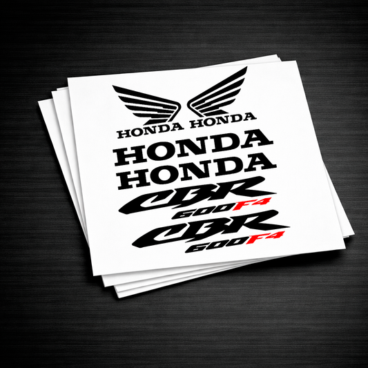 A stack of white decal stickers featuring the Honda logo and 'HONDA CBR 600 F4' text, displayed on a dark wood background.