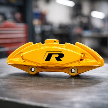 Yellow VW Volkswagen R-Line brake caliper with a brand logo on a blurred workshop background